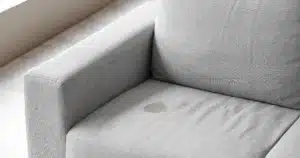 Een licht grijze bank met een vetvlek op de zitting