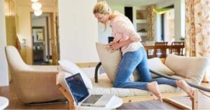 Een vrouw die een bank schoonmaakt met een stofzuiger