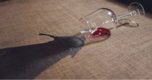 Een omgevallen glas rode wijn en een daardoor veroorzaakte vlek in de bank